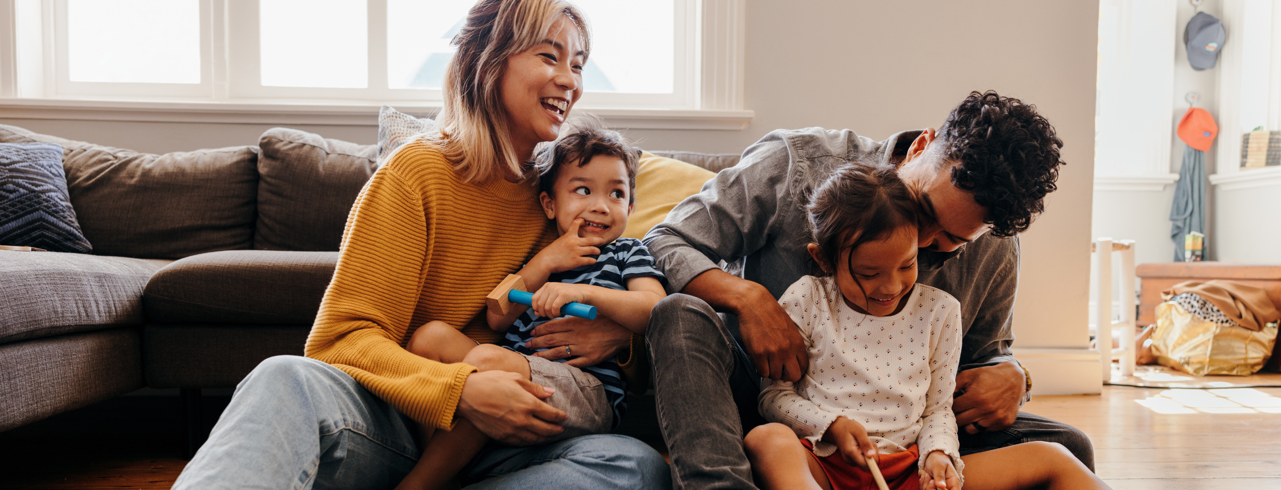 Young parents playing with their son and daughter in the living room. Mom and dad having fun with their children during playtime. Family of four spending some quality time together at home.